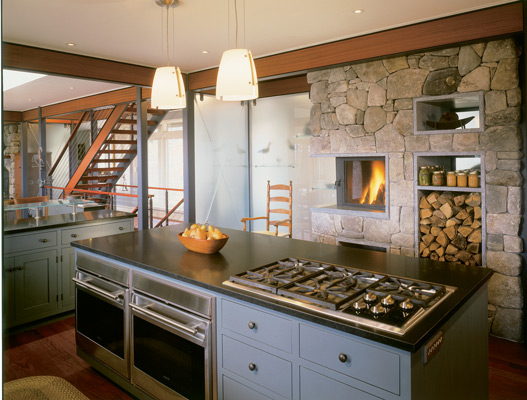 Maine stonework and firewood from the Grassis’ property give local, country flavor to the modern, energy-efficient kitchen. The countertops are stone, chosen because they’ll last longer than synthetics and can be reused in another home someday.